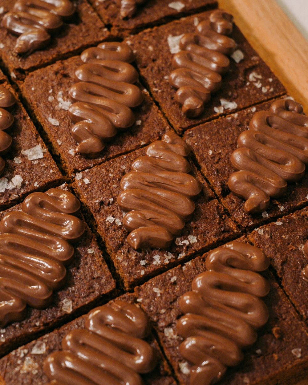 Brownies cortados en cuadros, cada uno con una línea de dulce de leche y escamas de sal encima.