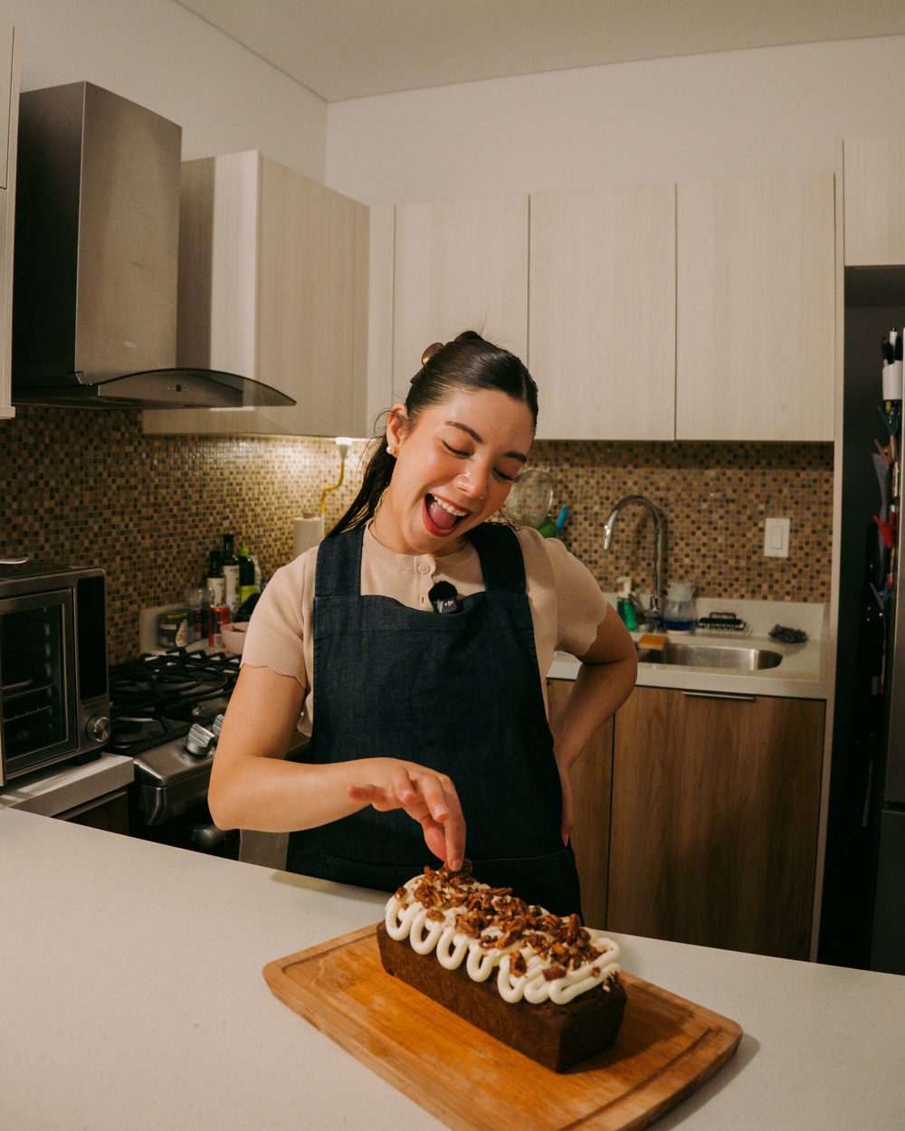 Marianna sacando la lengua mientras acomoda la nuez sobre el panqué recién decorado en la barra de la cocina.
