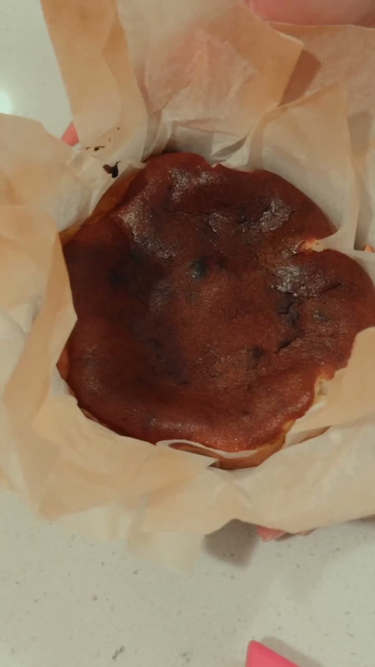 El cheesecake recién horneado, con la superficie quemada y el papel abierto.