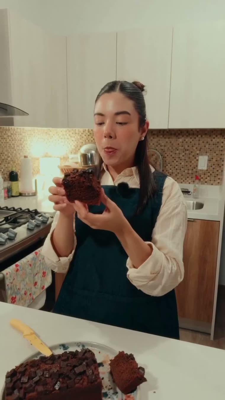 Marianna sostiene una rebanada del panqué, húmeda y oscura.