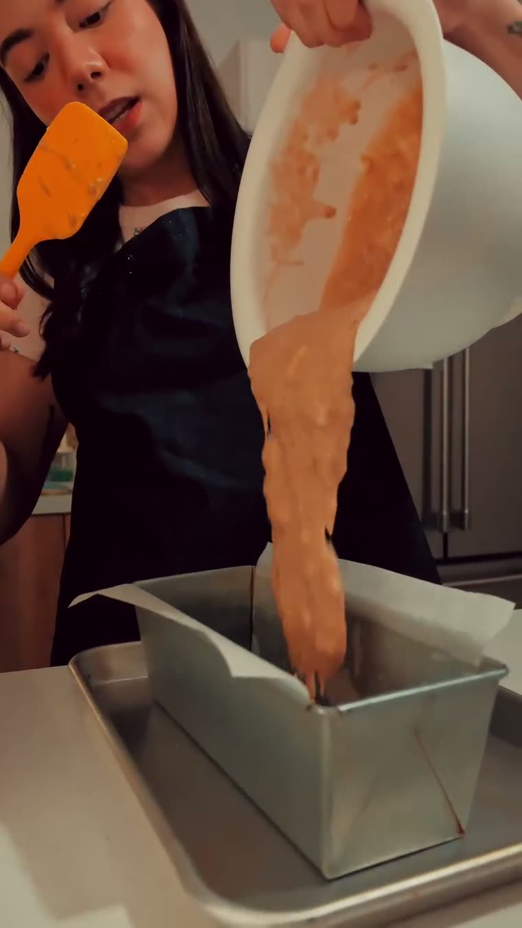 La mezcla cayendo dentro del molde forrado con papel.