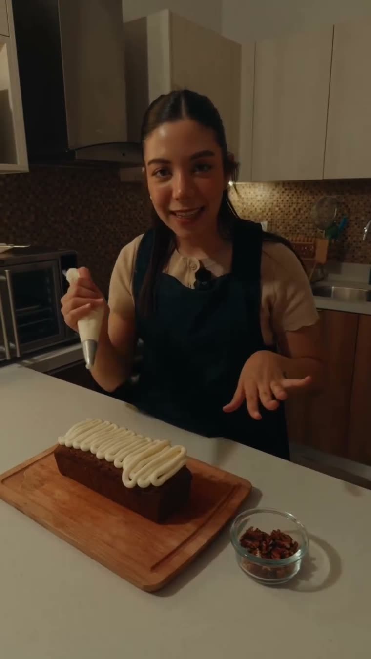 Marianna decora el panqué con la duya llena de betún.